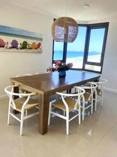 a dining room table and chairs with a view of the ocean at The Breakers in Gold Coast