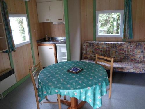 a small kitchen with a table and a table and chairs at Chalet confortable avec terrasse et jardin - API-1-52-889 in La Chapelle