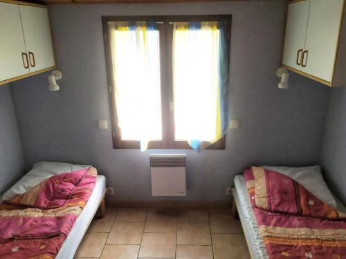 two beds in a room with a window at Chalet confortable avec terrasse - 4 personnes - API-1-52-908 in Saint-Rome-de-Tarn