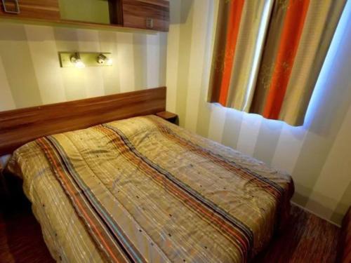 a bedroom with a bed and a window at Mobil home avec Terrasse - 3 Chambres, 6 Personnes - API-1-52-896 in Saint-Rome-de-Tarn