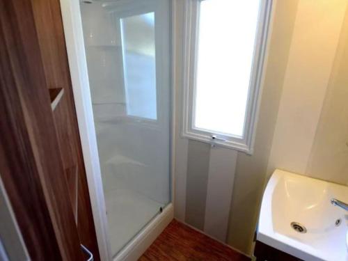 a bathroom with a shower and a sink and a window at Mobil home avec Terrasse - 3 Chambres, 6 Personnes - API-1-52-896 in Saint-Rome-de-Tarn