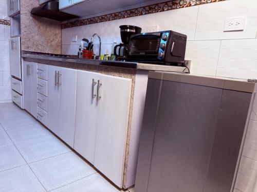a kitchen with white cabinets and a microwave on the counter at Posada Pa'sumerce in Tibasosa