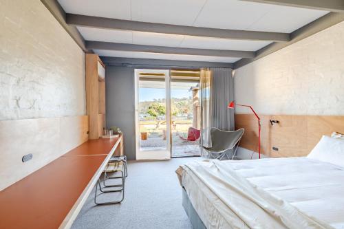 a bedroom with a bed and a desk and a window at Black Dolphin Motel in Merimbula