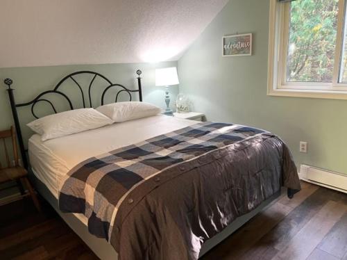 a bedroom with a bed with a blanket on it at Whispering Dunes At Singing Sands All Season in Tobermory