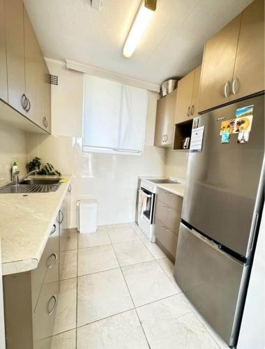 a kitchen with a stainless steel refrigerator and white cabinets at Waterfront Bliss Apartment in the Heart of Manly in Sydney