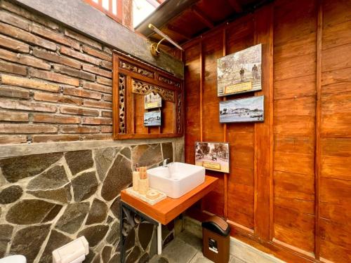 bagno con lavandino e parete in pietra di Nglaras Resort Yogyakarta a Ngaglik