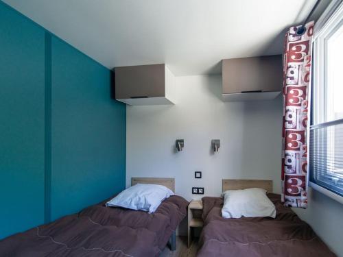 two beds in a room with blue walls at Mobil-home confortable avec terrasse pour 5 personnes - API-1-52-916 in Saint-Rome-de-Tarn