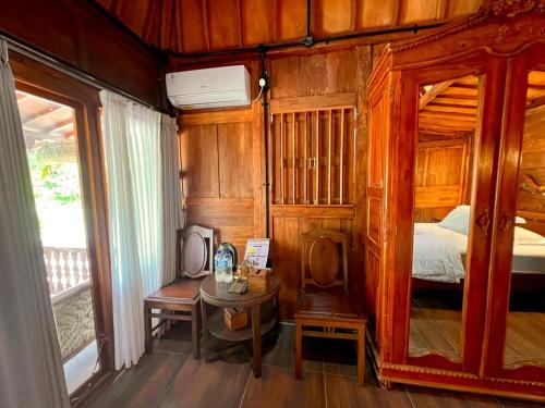 una camera da letto con un letto, un tavolo e uno specchio di Nglaras Resort Yogyakarta a Ngaglik