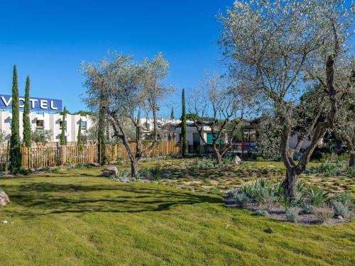 einen Garten mit Bäumen und Felsen im Hof in der Unterkunft Novotel Perpignan Nord Rivesaltes in Rivesaltes