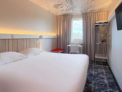 ein Schlafzimmer mit einem großen weißen Bett und einem Fenster in der Unterkunft ibis Rennes Cesson in Cesson-Sévigné