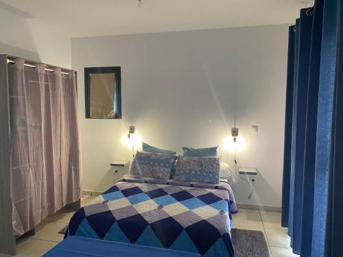 sypialnia z łóżkiem z niebiesko-białym kocem w obiekcie Les Zamours Des Lianes w mieście Saint-Joseph