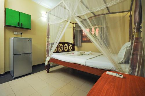 a bedroom with a canopy bed and a refrigerator at Green Villa in Kahawa
