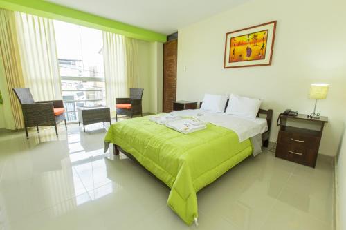 a bedroom with a green bed and a table and chairs at Hostal Florida in Chiclayo