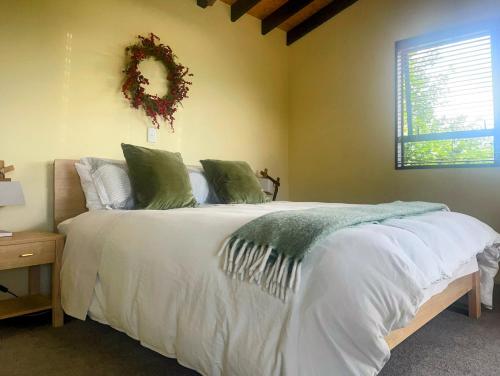 um quarto com uma cama branca e uma coroa de flores na parede em TekapoB2 Lakeview Apartment em Lake Tekapo