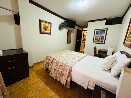 a bedroom with a white bed and a dresser at Hospedaje El Escudero in Trujillo