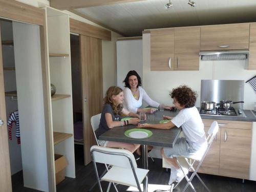 Chalet avec Terrasse à Soubès - Accès Handicapé - API-1-52-955 في Soubès: ثلاثة أشخاص يجلسون على طاولة في مطبخ