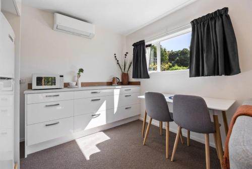 a kitchen with white cabinets and a table and chairs at Best of Both Worlds Between City & Sea Holiday House in Nelson