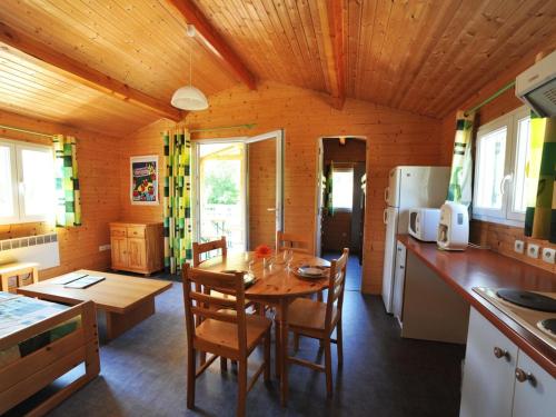 a kitchen and dining room with a table and chairs at Chalet pour 6 pers avec terrasse au Domaine du Lac de Champos - API-1-52-1001 in Charmes-sur-lʼHerbasse