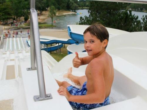 a young boy sitting in a bathtub giving a thumbs up at Chalet pour 6 pers avec terrasse au Domaine du Lac de Champos - API-1-52-1001 in Charmes-sur-lʼHerbasse