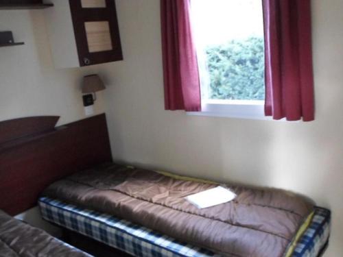 a small bed in a room with a window at Mobil-home 6 personnes avec terrasse à La Chapelle-devant-Bruyères - API-1-52-1002 in La Chapelle