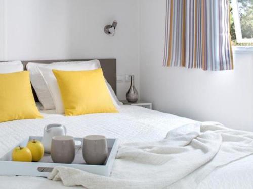 ein weißes Bett mit einem Tablett mit Obst darauf. in der Unterkunft Mobil home confortable avec terrasse - API-1-52-1015 in Port Blanc