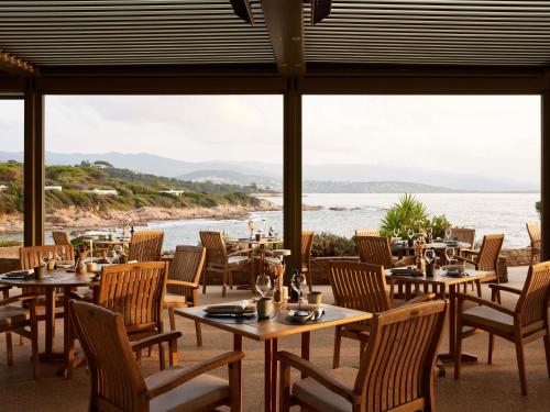 a restaurant with tables and chairs and a view of the ocean at Sofitel Golfe d'Ajaccio Thalassa Sea & Spa in Ajaccio