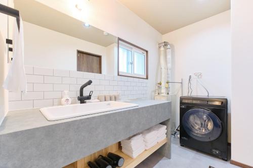 a bathroom with a sink and a washing machine at Casa Katatsumuri in Nakafurano