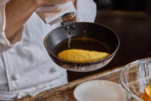 小樽市にあるグランドパーク小樽の食べ物が入ったフライパンを持っている人