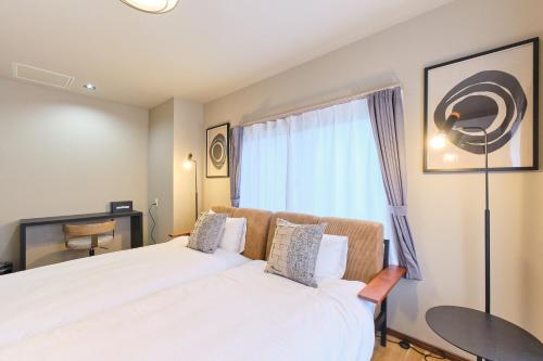 a bedroom with two beds and a window at Casa Katatsumuri in Nakafurano