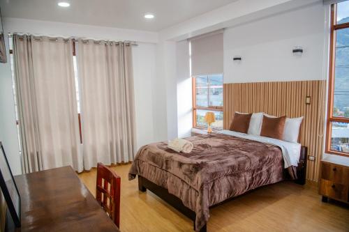 a bedroom with a bed and a table and windows at HOTEL TERRANOVA Abancay in Abancay