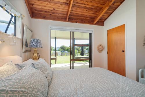 a bedroom with a bed and a door to a yard at Hosts on the Coast Paws & Relax Bach in Hahei