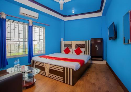 Sumeru Hotel and Lodge في Itahari: غرفة نوم زرقاء مع سرير وطاولة زجاجية