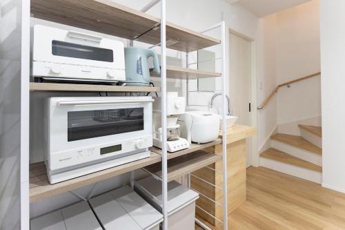a kitchen with a microwave and appliances on a shelf at T-Tarry Stay Villa in Sapporo