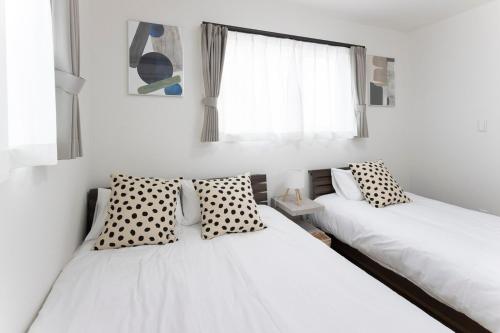 two beds in a room with white walls at T-Tarry Stay Villa in Sapporo