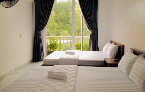 two beds in a room with a window at Hiên's Homestay in Hue