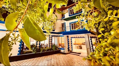 a house with blue and white walls and a tree at MGallery Hotel in Srinagar