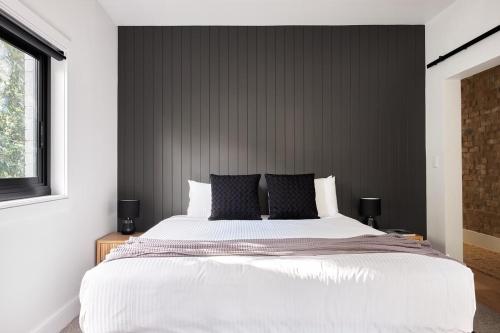 a bedroom with a large bed with a black wall at Bondi Beach Premium Hideaway - Premium 2 bed apartment in Sydney