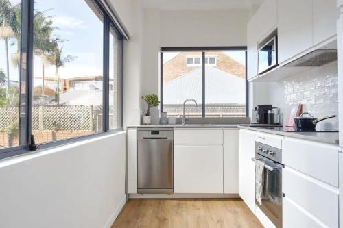 a kitchen with white cabinets and a large window at Manly Cosy Retreat - Short walk to beach in Sydney