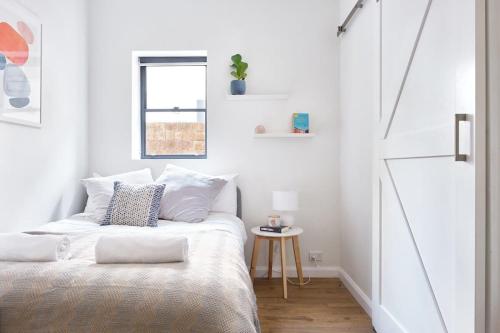 a white bedroom with a bed and a window at Manly Cosy Retreat - Short walk to beach in Sydney