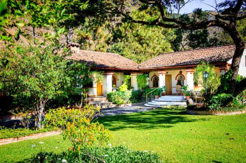 a house with a garden and a yard with trees at Regis Hotel Spa in Panajachel