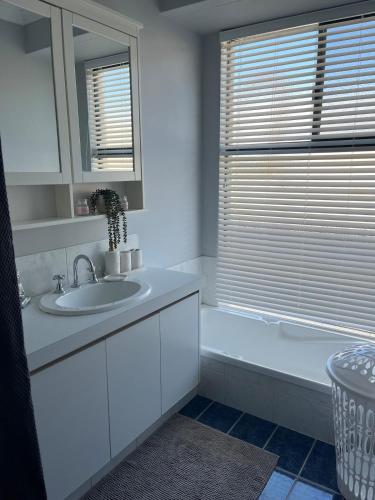 a white bathroom with a sink and a mirror at Hibiscus Haven in Eaton