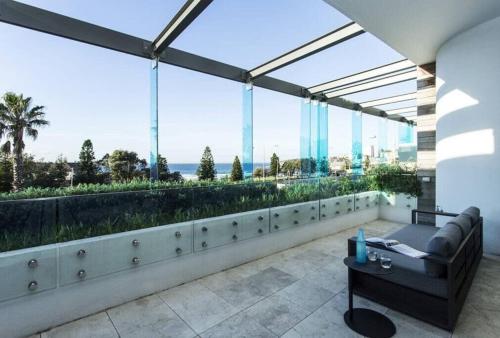 a room with a couch and a table on a balcony at Luxury Bondi Beachside Apartment - Pacific in Sydney