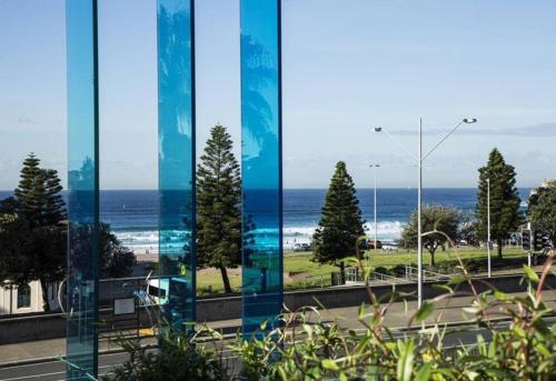 a view of the ocean from a glass building at Luxury Bondi Beachside Apartment - Pacific in Sydney