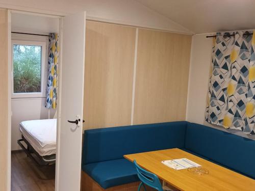 a room with a blue couch and a table and a bed at Mobil-home confortable avec terrasse - API-1-52-1100 in Luynes
