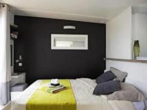 a bedroom with a bed with a black wall at Mobil-home de 32m² avec terrasse et équipements de cuisine - API-1-52-1126 in Loudéac