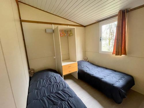 Una pequeña habitación con dos camas y una ventana. en Chalet de 26m² avec Terrasse pour 4 Personnes - API-1-52-1070, en Belloc