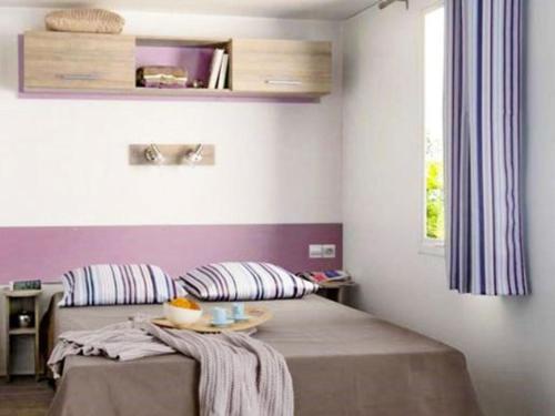 a bedroom with a bed with a table on it at Mobil-home avec terrasse à Luynes - API-1-52-1072 in Luynes