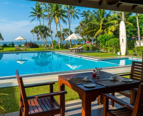 a table and chairs next to a swimming pool at Borala Lake Weligama in Weligama