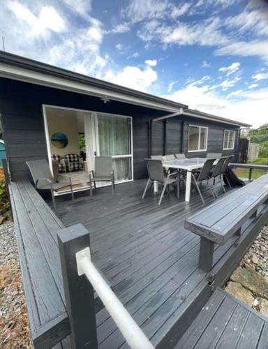een houten terras met een tafel en een bank bij Gordonton Greenmeadows Cottage in Taupiri
