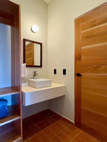 a bathroom with a sink and a mirror and a door at Cabañas Las Camelias in Cuetzalán del Progreso
